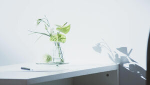 自然光に照らされたデスクと花。余白を生かした落ち着いたミニマルデザインの風景
