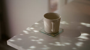 光の差すテーブルに置かれた白いマグカップ
